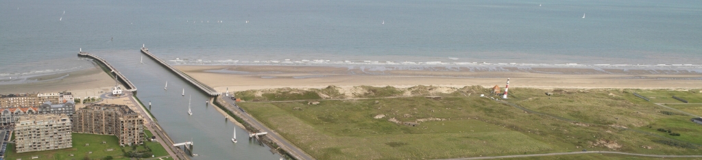 Luchtfoto van een waterweg die uitkomt in de Belgische kust.